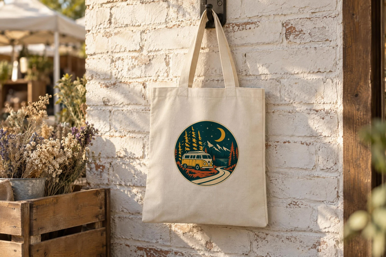 A cream tote hanging from a hook on a whitewashed brick wall at a market, rendered by SudoMock with the round camper van badge on its front panel