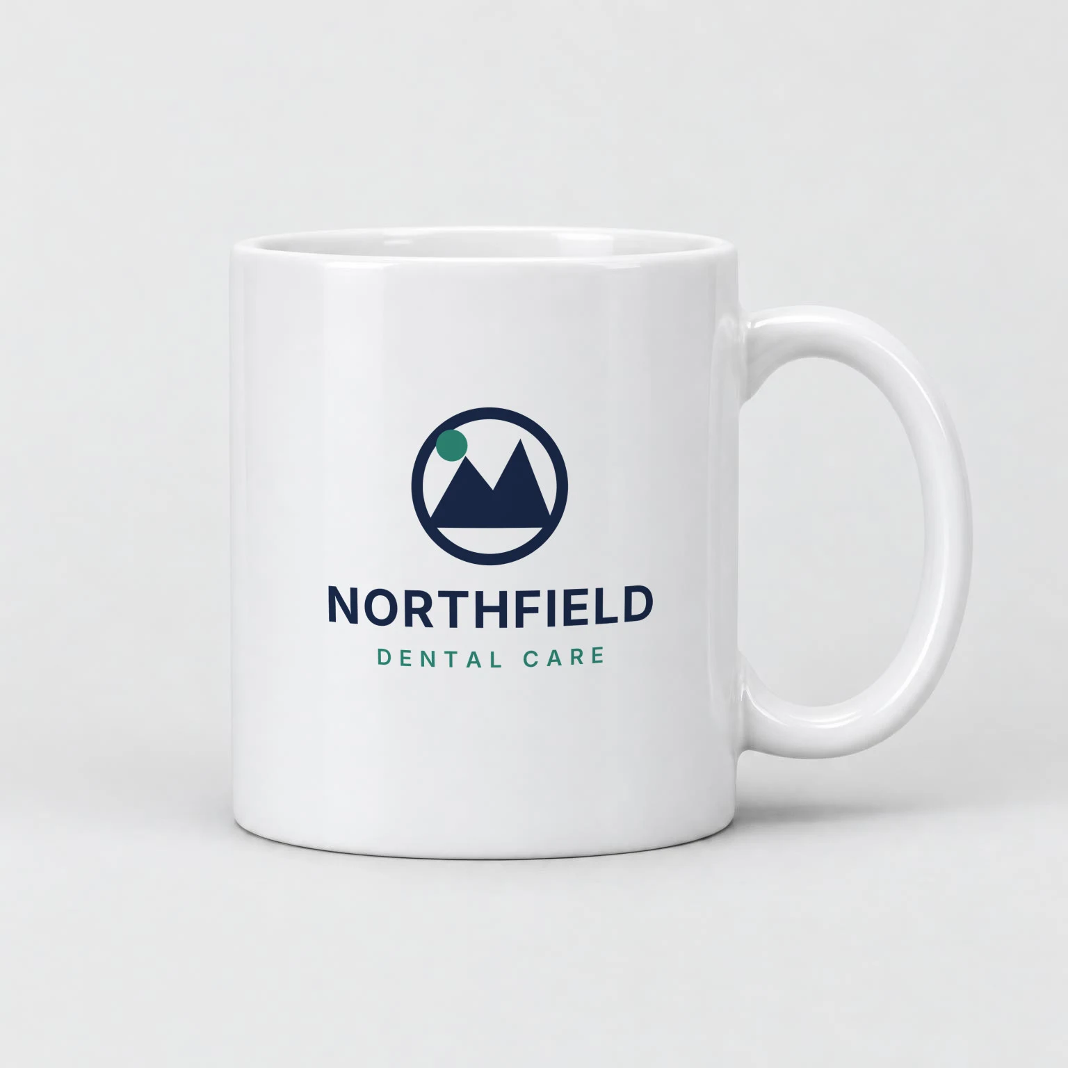 White 11 oz ceramic mug rendered by SudoMock with the Northfield Dental Care logo, a navy ring with mountain peaks and a green sun above the wordmark, centered on the side facing the camera