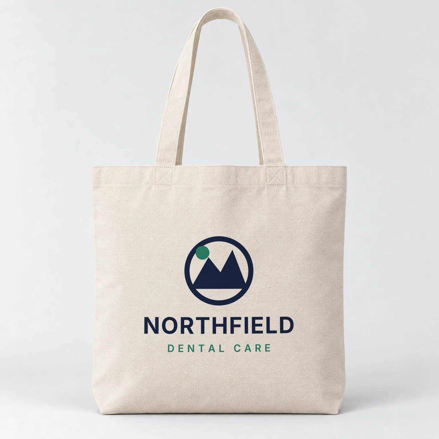 Natural cotton canvas tote rendered by SudoMock with the Northfield Dental Care logo in navy and green centered on the front panel below the handles